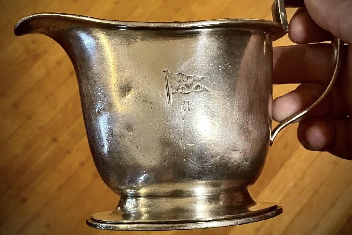 Silverplate creamer with White Star Line-style flag motif and maker’s mark; side view with handle and spout