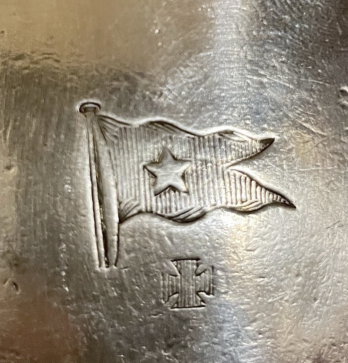Close-up of the stamped flag motif and maker mark on the creamer body